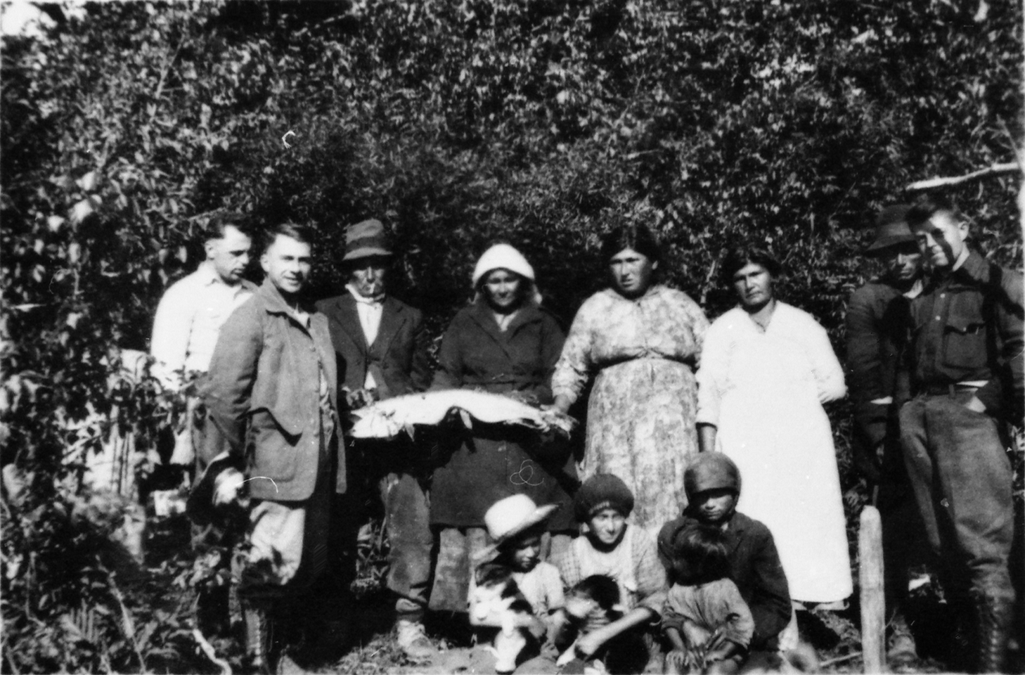 Photo d'un groupe de 11 autochtones, possiblement des Anicinabeg, à leur campement sur le bord de la rivière Kinojévis, 1925.