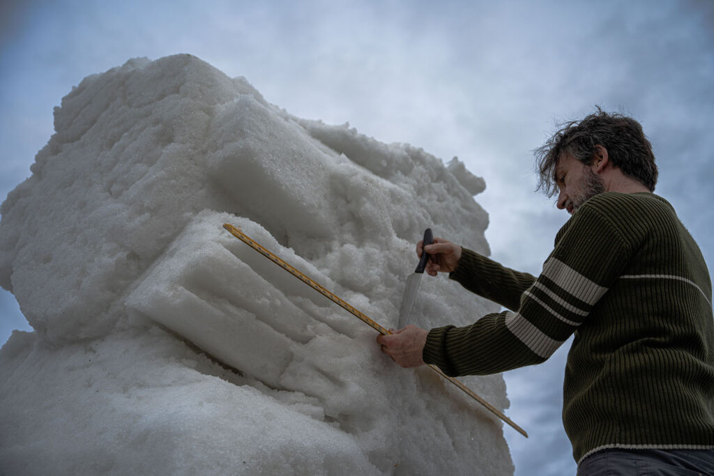 L'artiste Sébastien Ouellet en train de sculpter un bloc de neige.